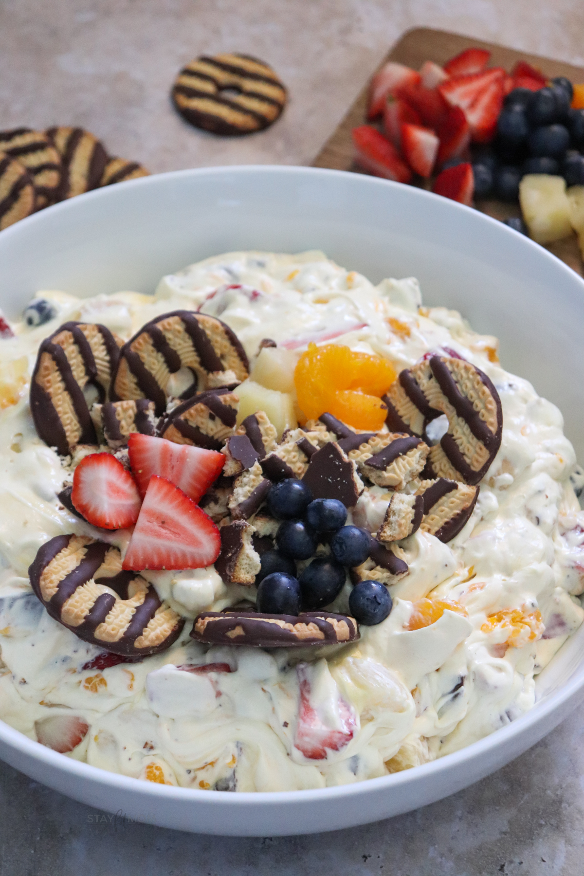 Cookie fruit salad showing completed recipe topped with fudge stripe bookies, strawberries, blueberries, mandarin oranges, and pineapple.
