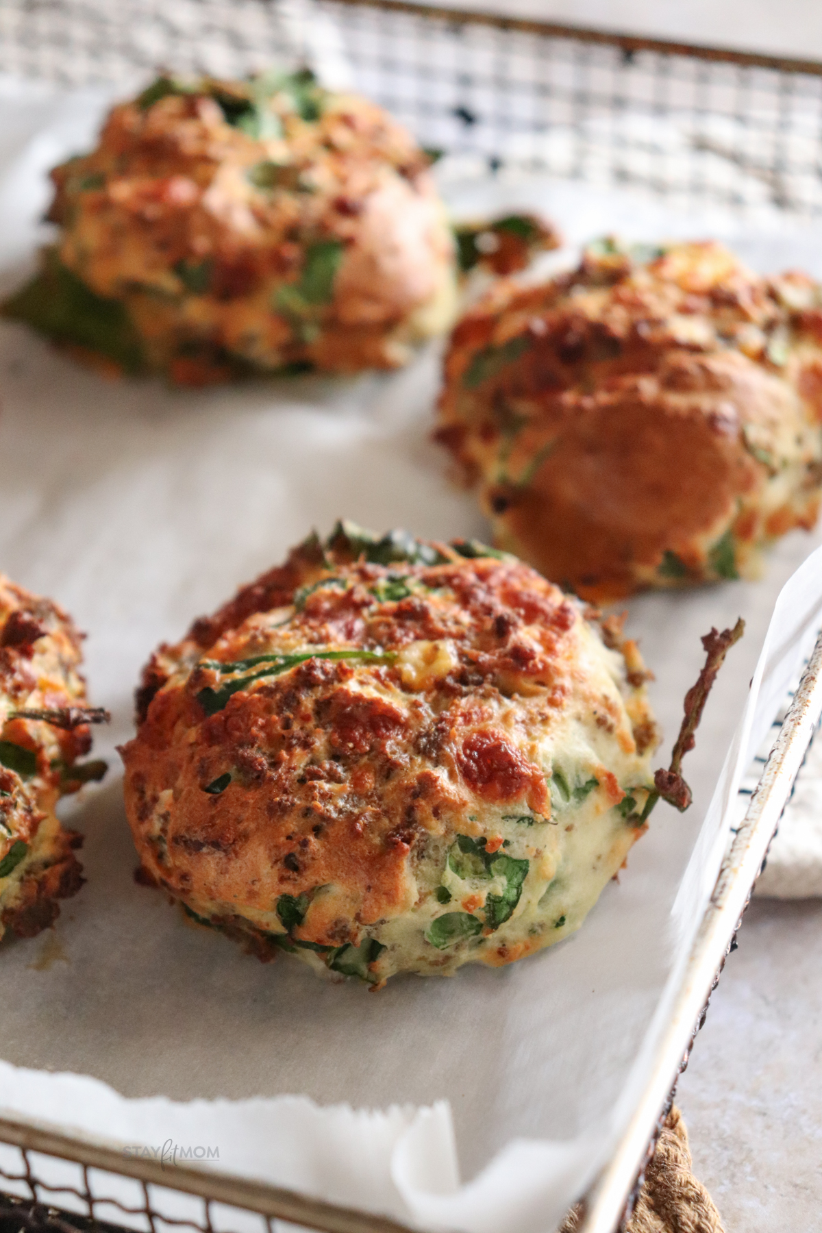 Cheesy sausage biscuits showing completed recipe with visible spinach, cheese, and crumbled breakfast sausage baked to perfection.