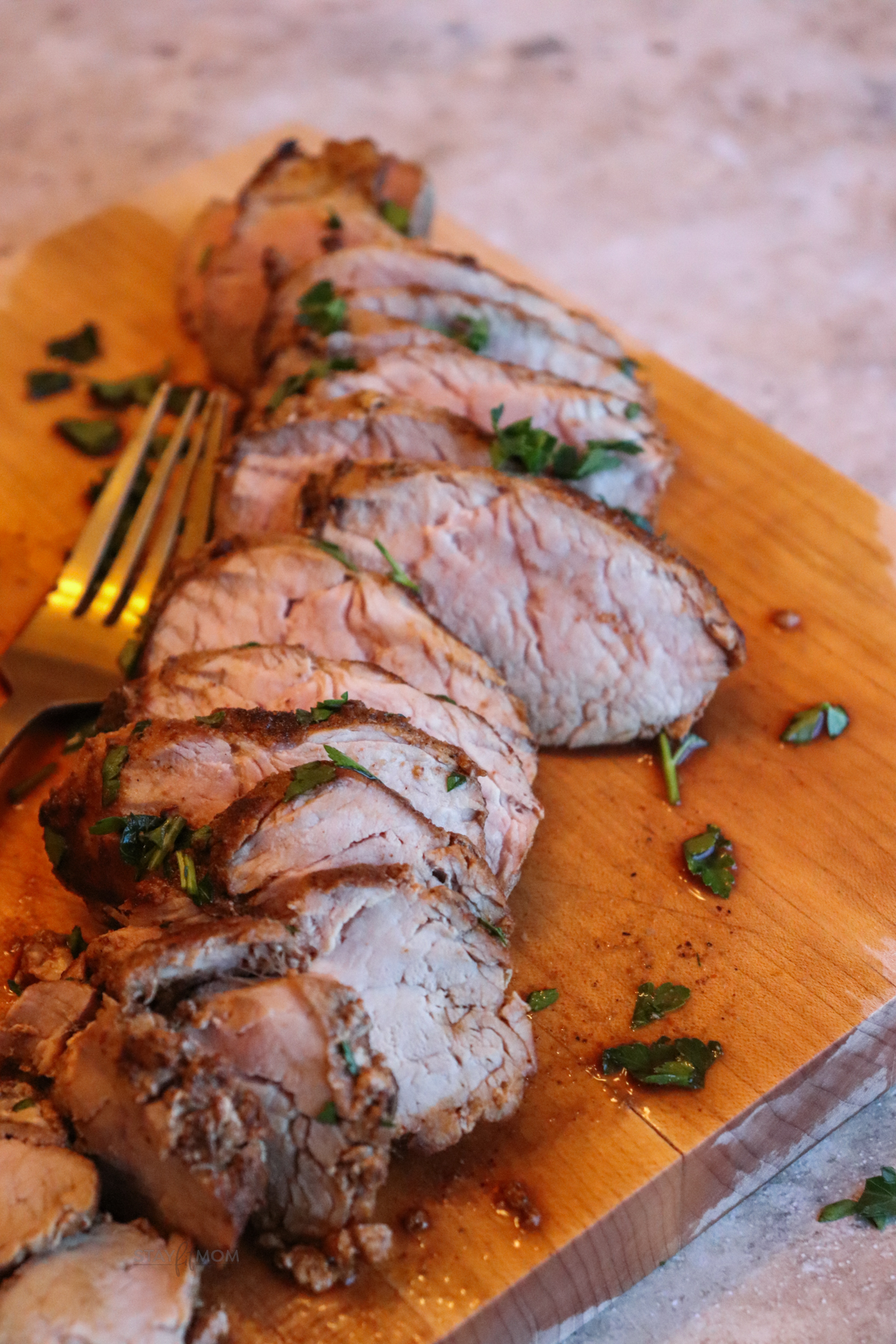 Pork tenderloin cooked and sliced on a cutting board.