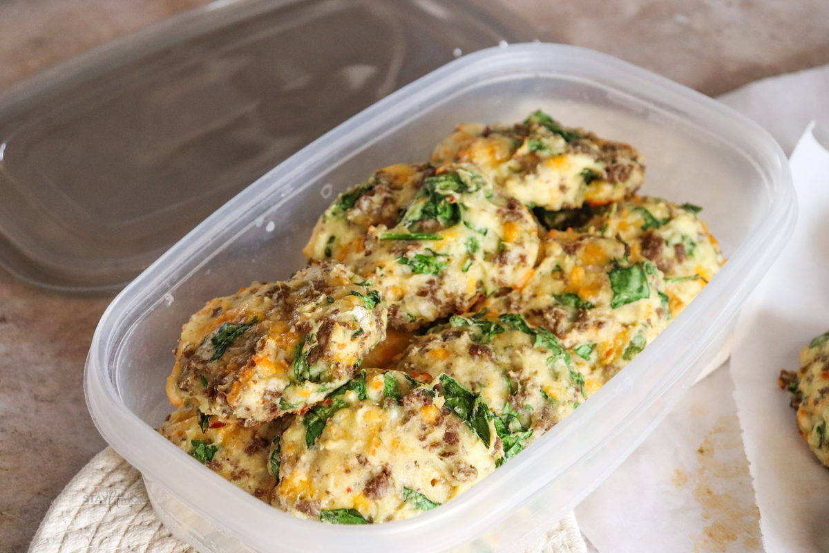 A meal prep container loaded up with cheesy sausage biscuits ready for the week.