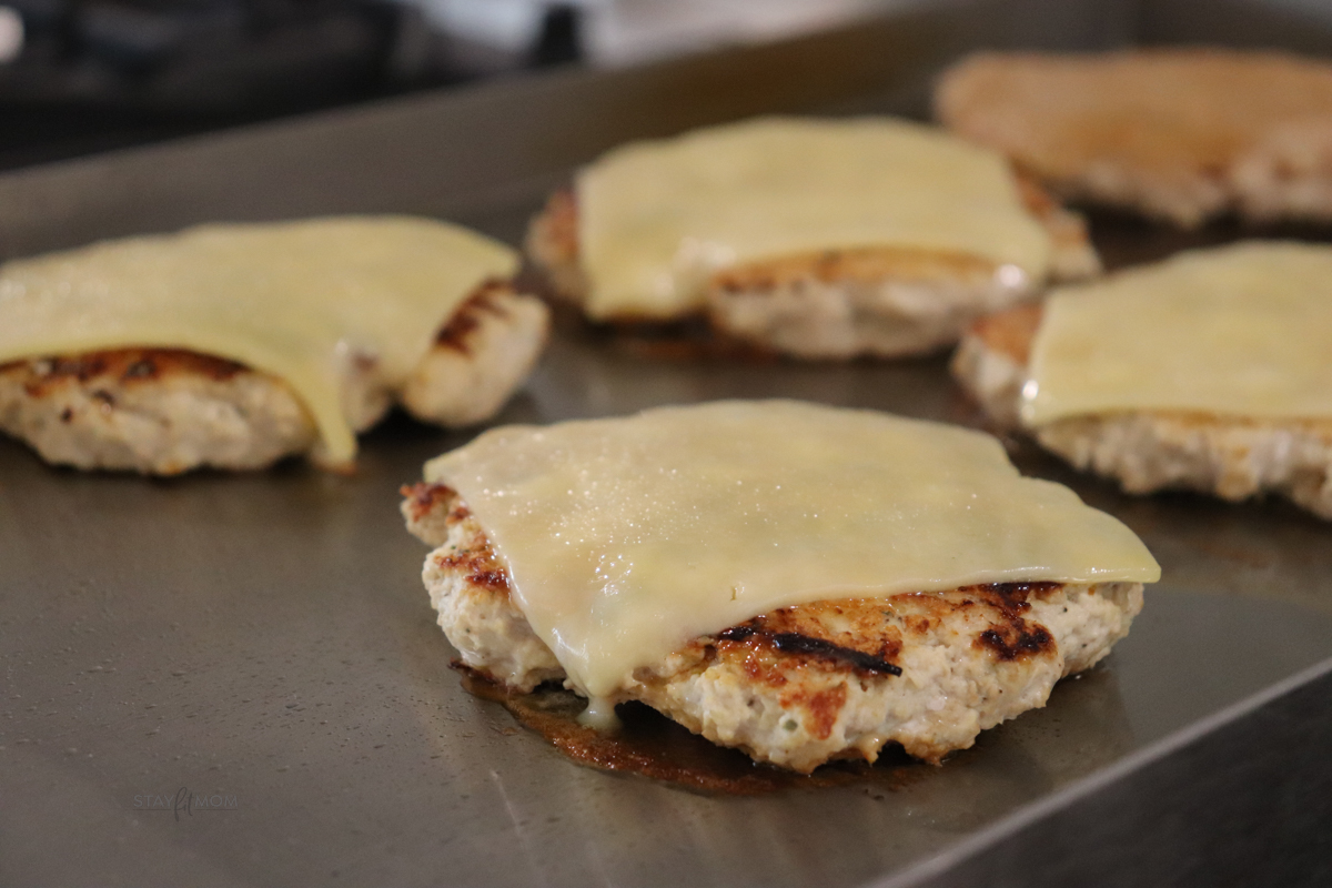 Grilled chicken patties with a slice of cheese melting on top.