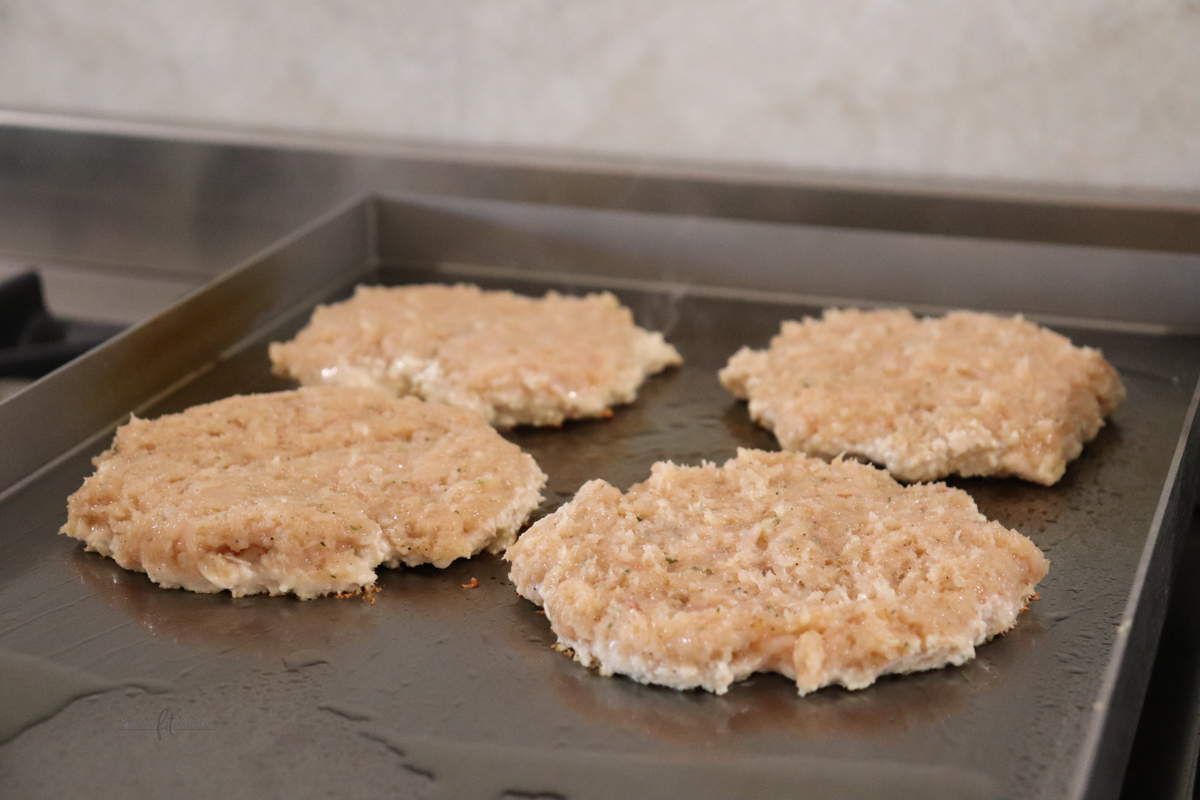Chicken patties being grilled on the flat top.