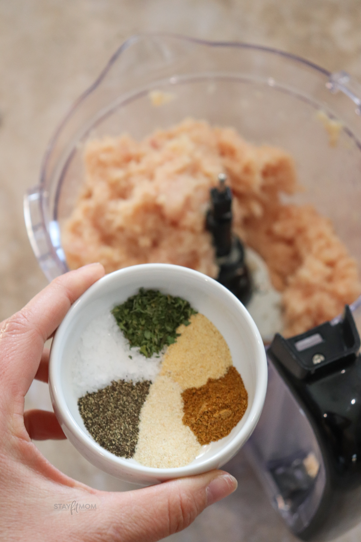 Chicken Patties showing a blurred food processor with ground chicken and a bowl of spices in the foreground.