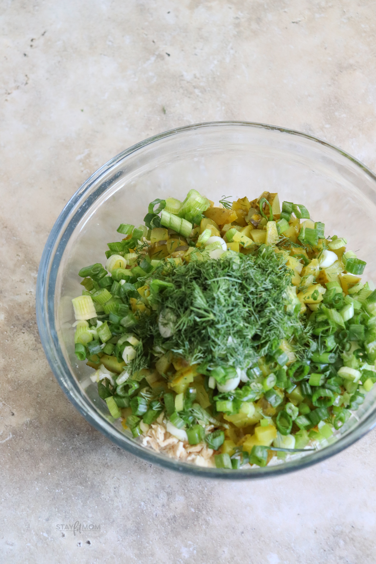 Small mixing bowl with ingredients for dill chicken salad layered in and ready to be stirred together.