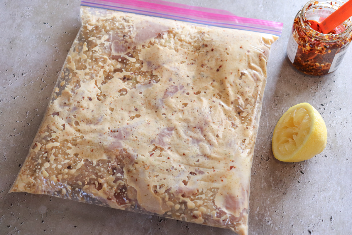 Crunchy onion loaf pan chicken showing ziploc bag with chicken thighs in marinade.