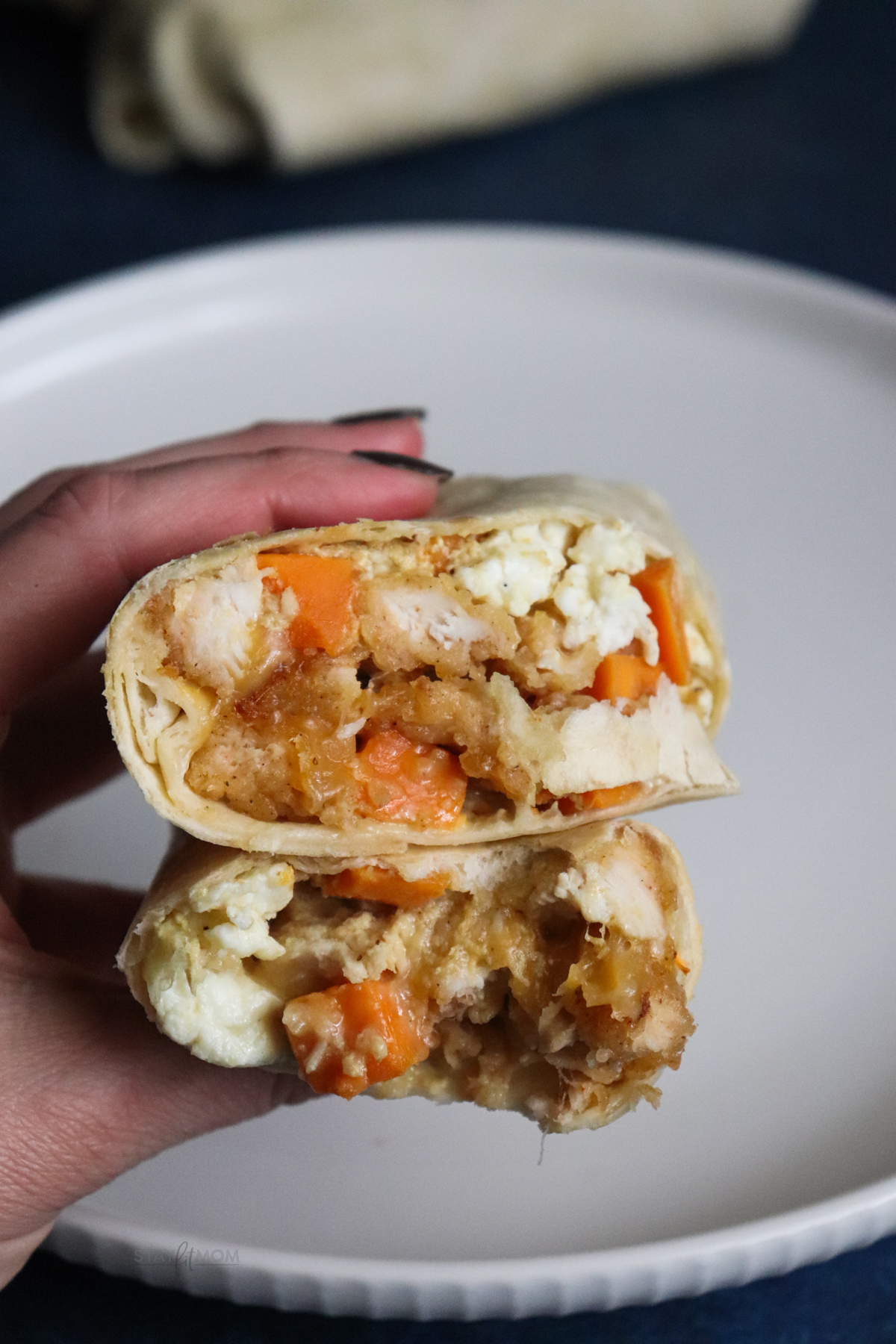 Crispy chicken breakfast burrito showing finished burrito cut in half to show filling.