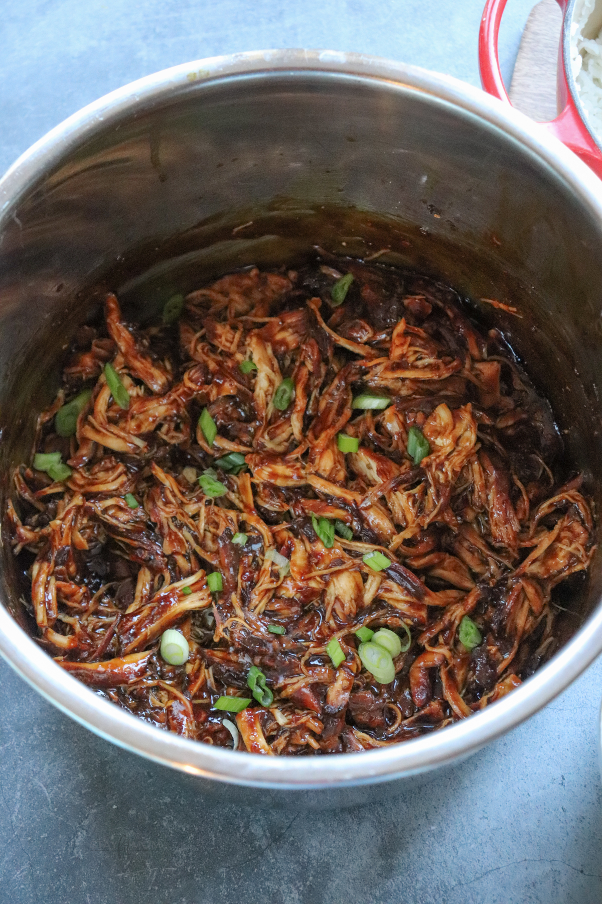 Teriyaki Chicken showing instant pot full of cooked, shredded teriyaki chicken.