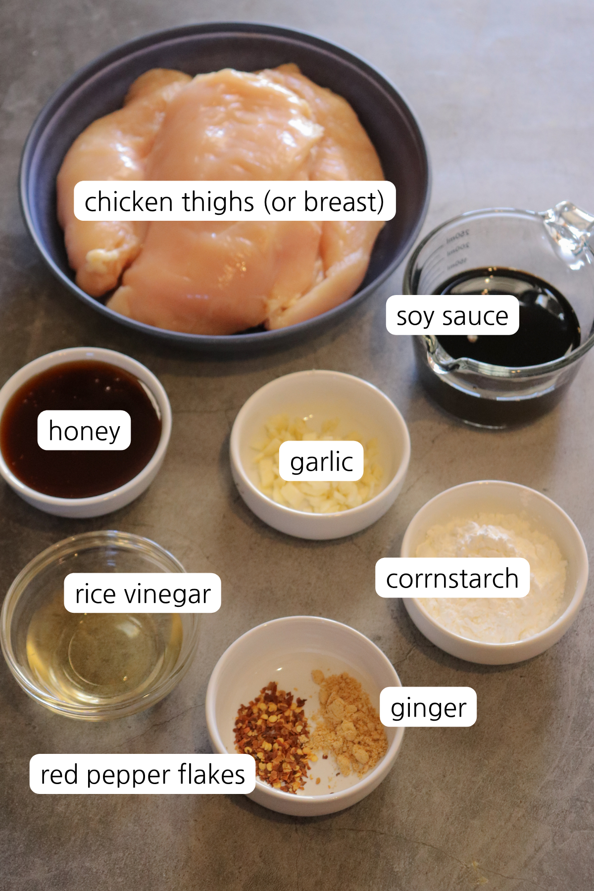 Teriyaki chicken ingredients labeled in small bowls: chicken thighs, soy sauce, garlic, honey, rice vinegar, ginger, cornstarch, and red pepper flakes.
