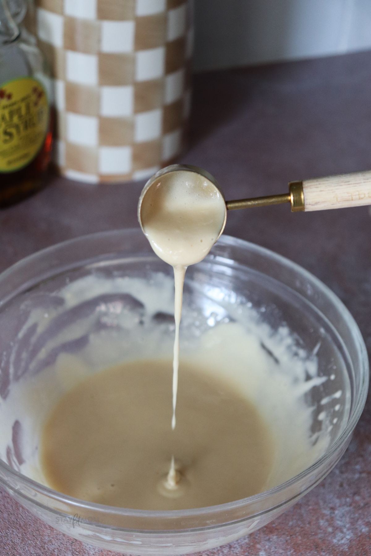 Maple Cinnamon muffins showing a bowl with gaze being drizzled out of a small ladle.
