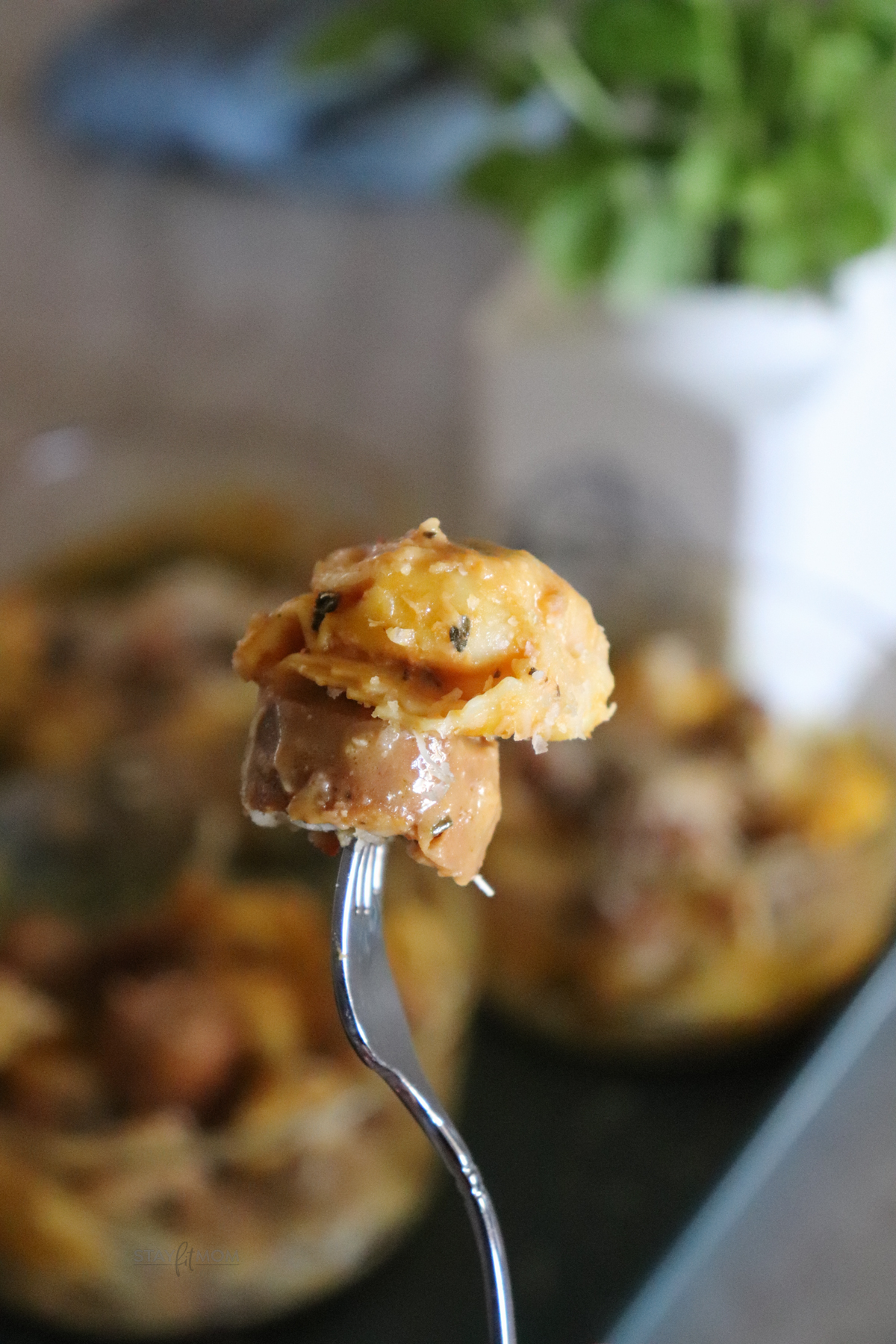 A fork in the foreground showing a bite of chicken sausage and tortellini.