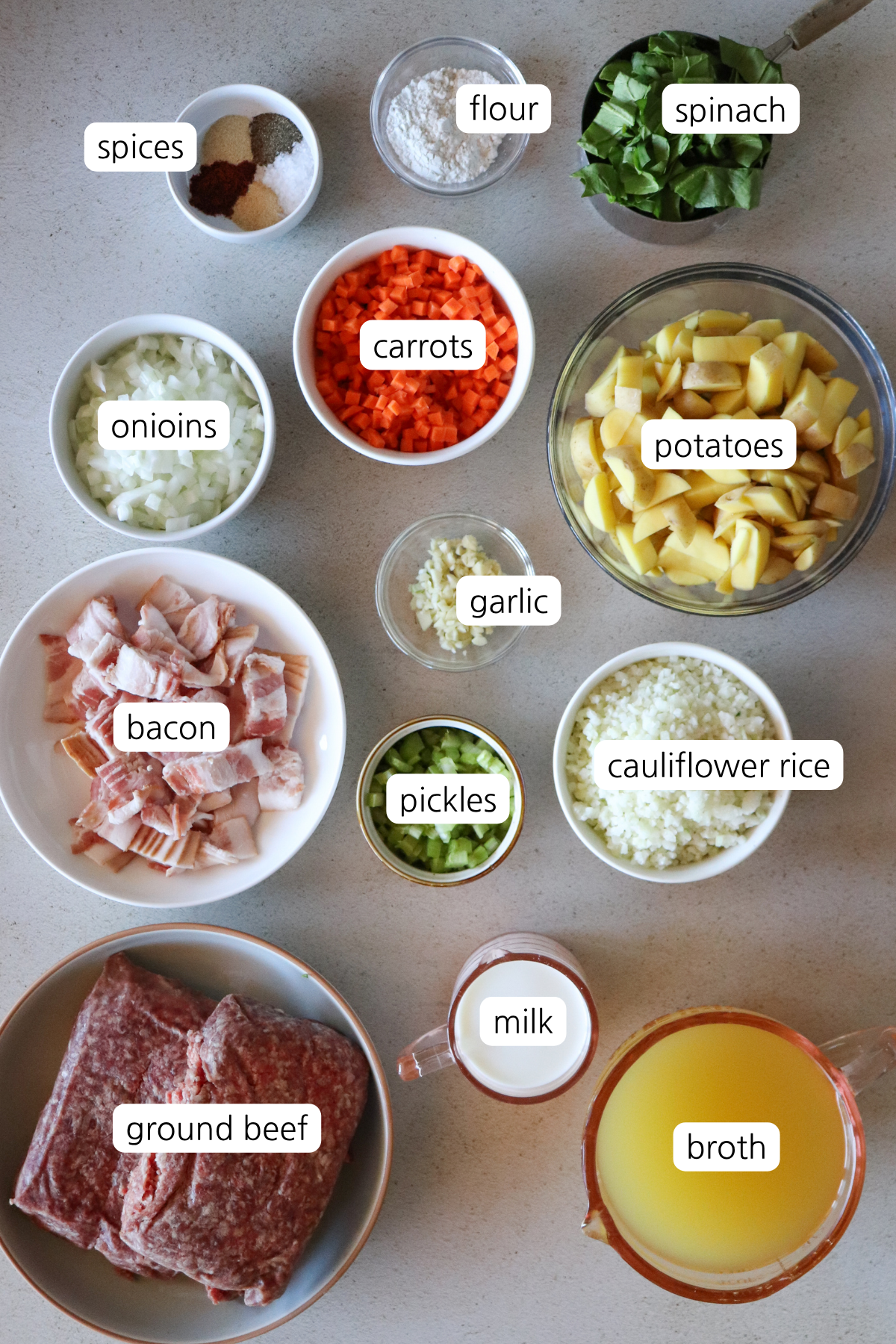 Cheeseburger soup showing ingredients labeled in small bowls.