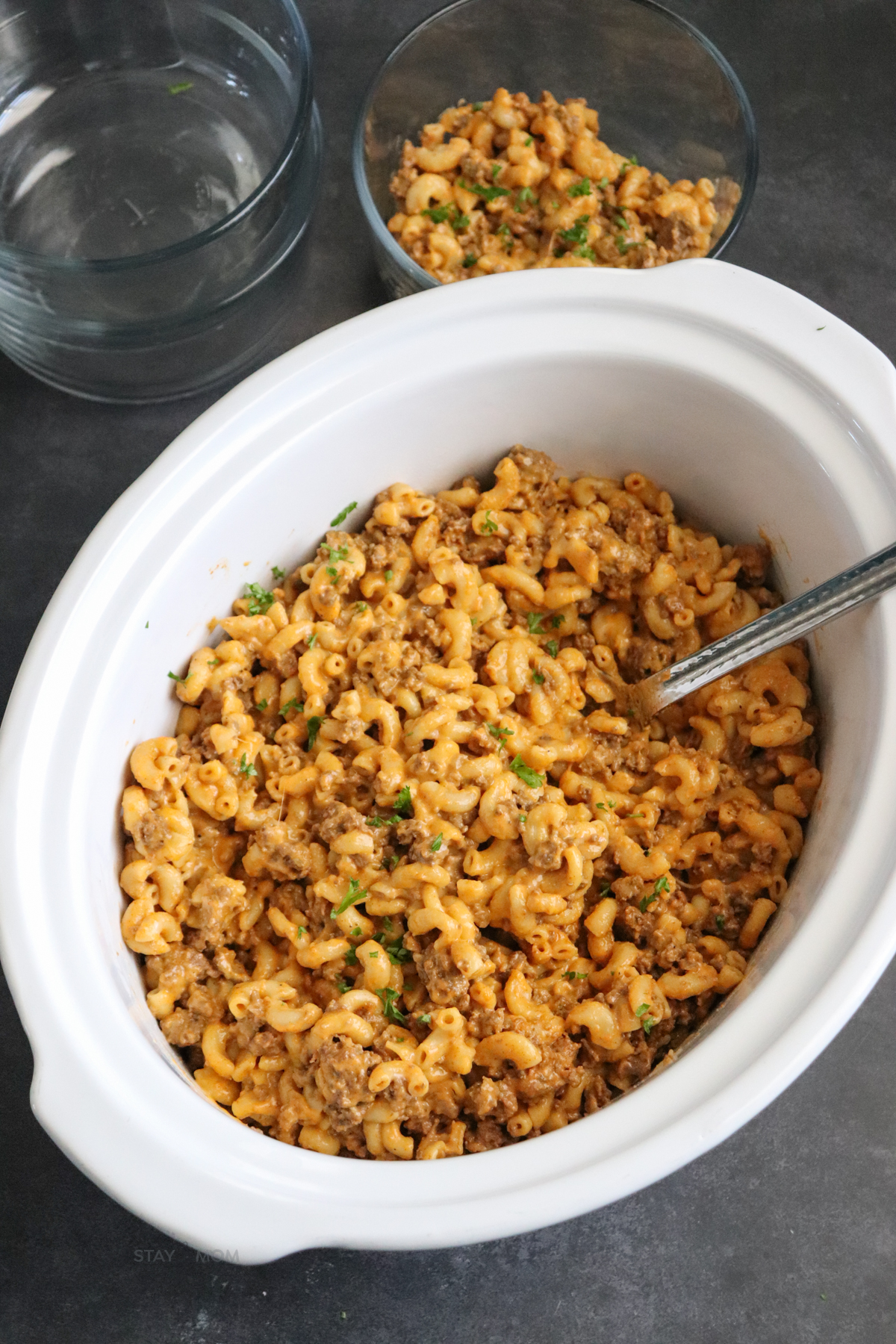 Hamburger Mac showing a white crock with finished recipe with elbow noodles, ground beef, and a cheesy sauce.