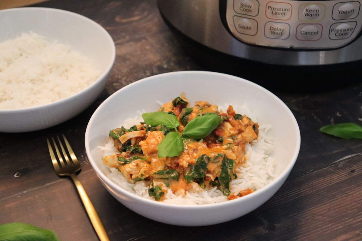 Marry Me Chicken showing completed recipe served over rice in a white bowl with another serving or rice in the background and the Instant Pot.