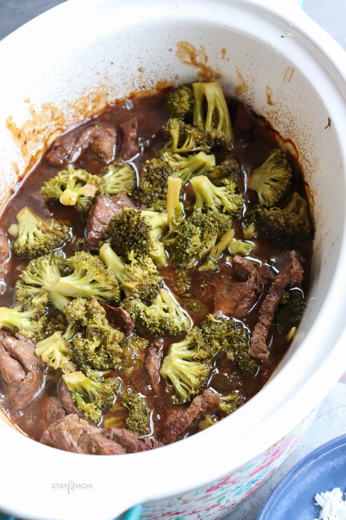 Slow cooker showing finished recipe with visible sliced chuck roast, cooked broccoli, and sauce.