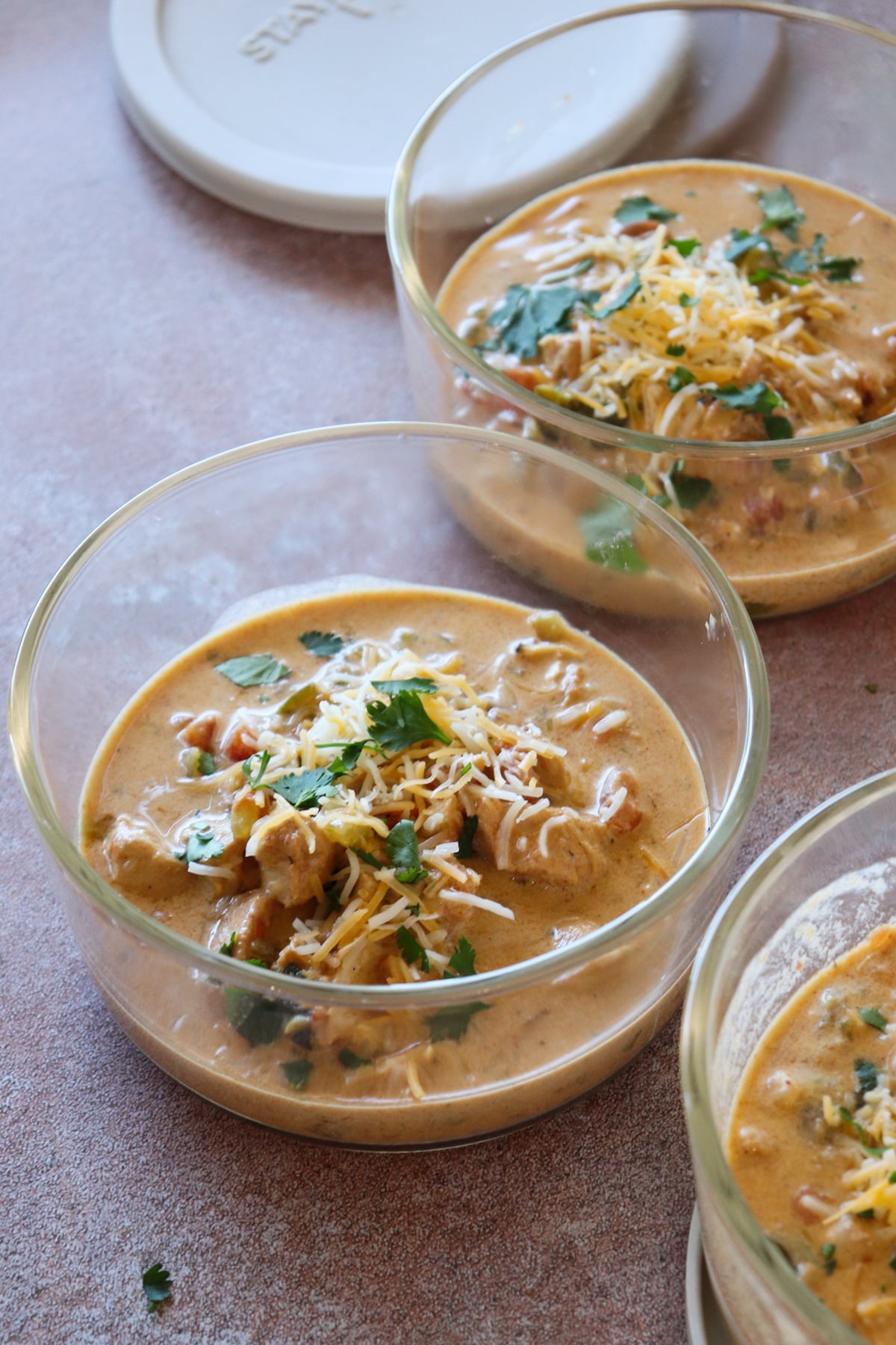 3 glass meal prep bowls with finished recipe topped with cheese.